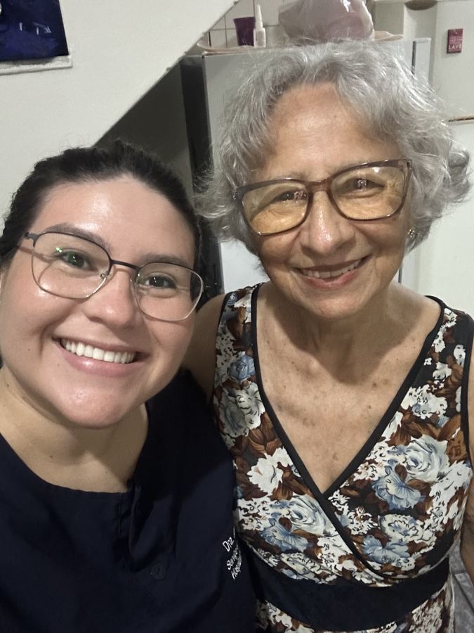 Dra. Jéssika Brito com paciente idosa sorridente após atendimento odontológico domiciliar em Manaus